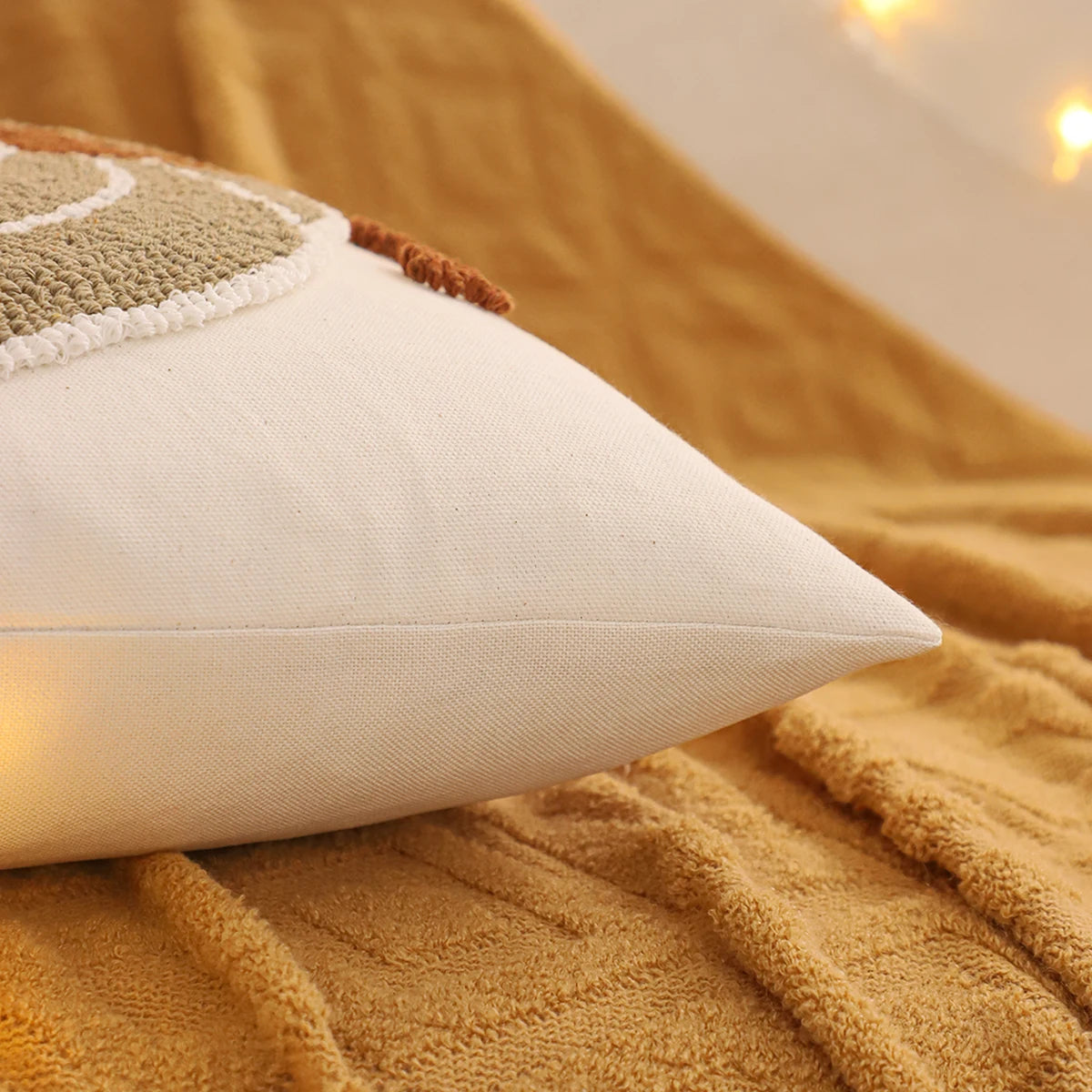 Beige pillow on a textured brown blanket with a warm glow in the background. Festive fall pillow cover for Halloween and Thanksgiving décor