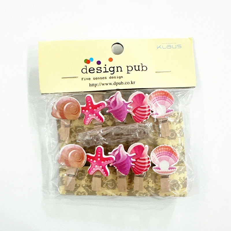 Packaged set of decorative clips with shell and starfish designs, brand 'design pub' visible.