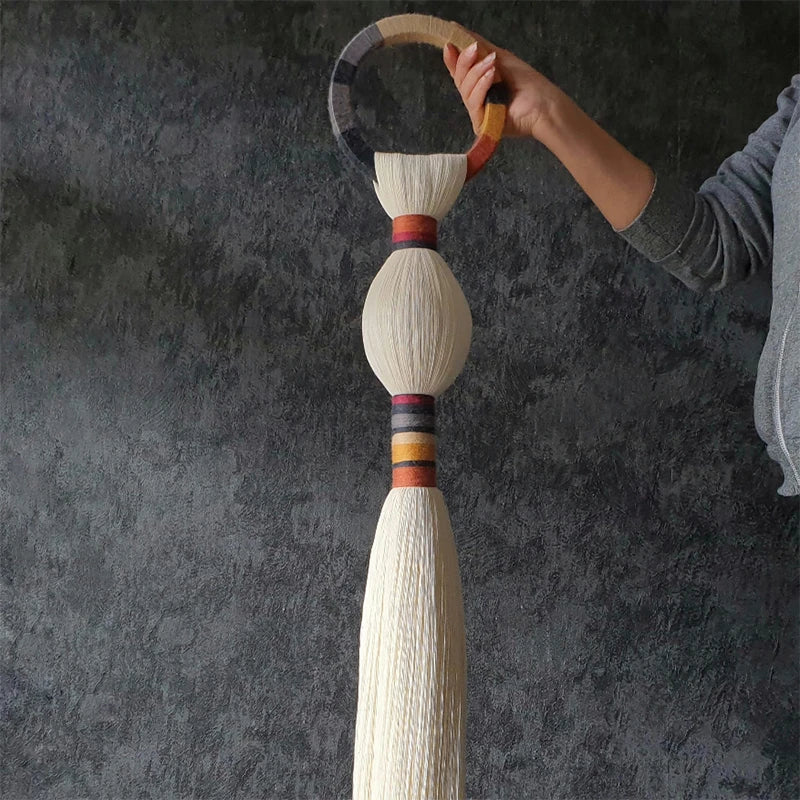 Hand holding a decorative item with a textured background. boho macrame wall art