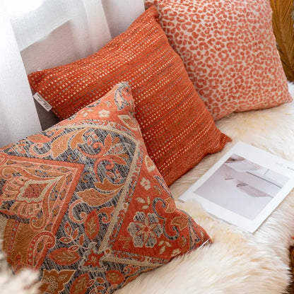 Decorative pillows on a sofa with a patterned pillow and a plain one.