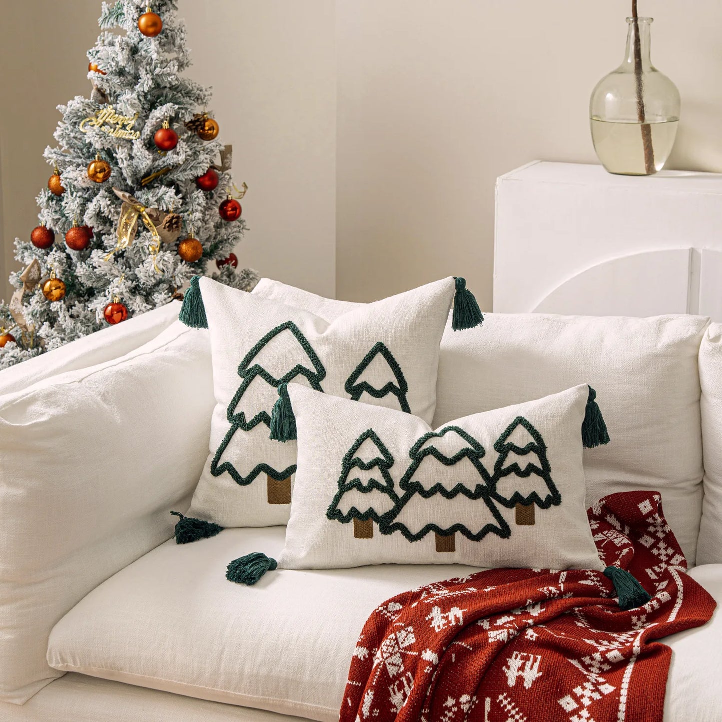 Decorative pillows with Christmas tree patterns on a white couch next to a decorated Christmas tree. tufted Christmas pillow cover with tassels, decorative festive cushion case for sofa or bed in 12x20 or 18x18 inches.