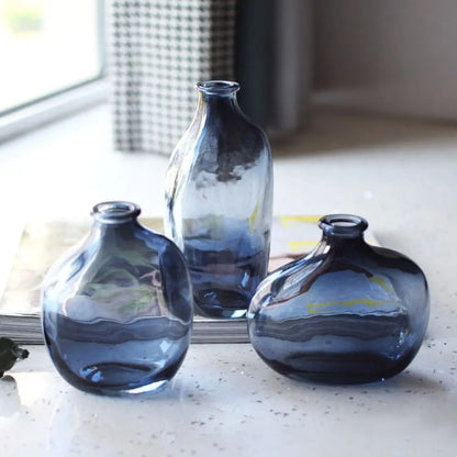 Three blue glass vases on a windowsill with a blurred background. Boho Living Room decor.