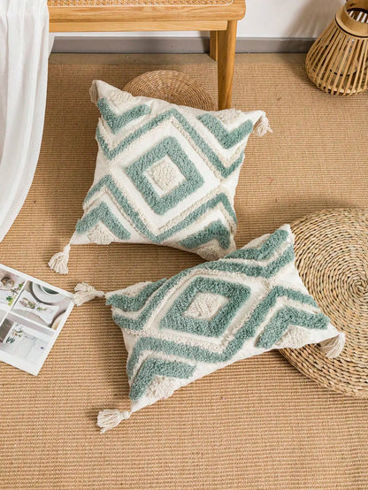 Two patterned pillows on a woven mat with a wooden table and lantern in the background. Nordic Moroccan tufted throw pillow cover in geometric jacquard design, boho accent cushion for sofa, bed, or car, available in 12x20 inch lumbar and 18x18 inch square sizes – cozy textured boho home decor.