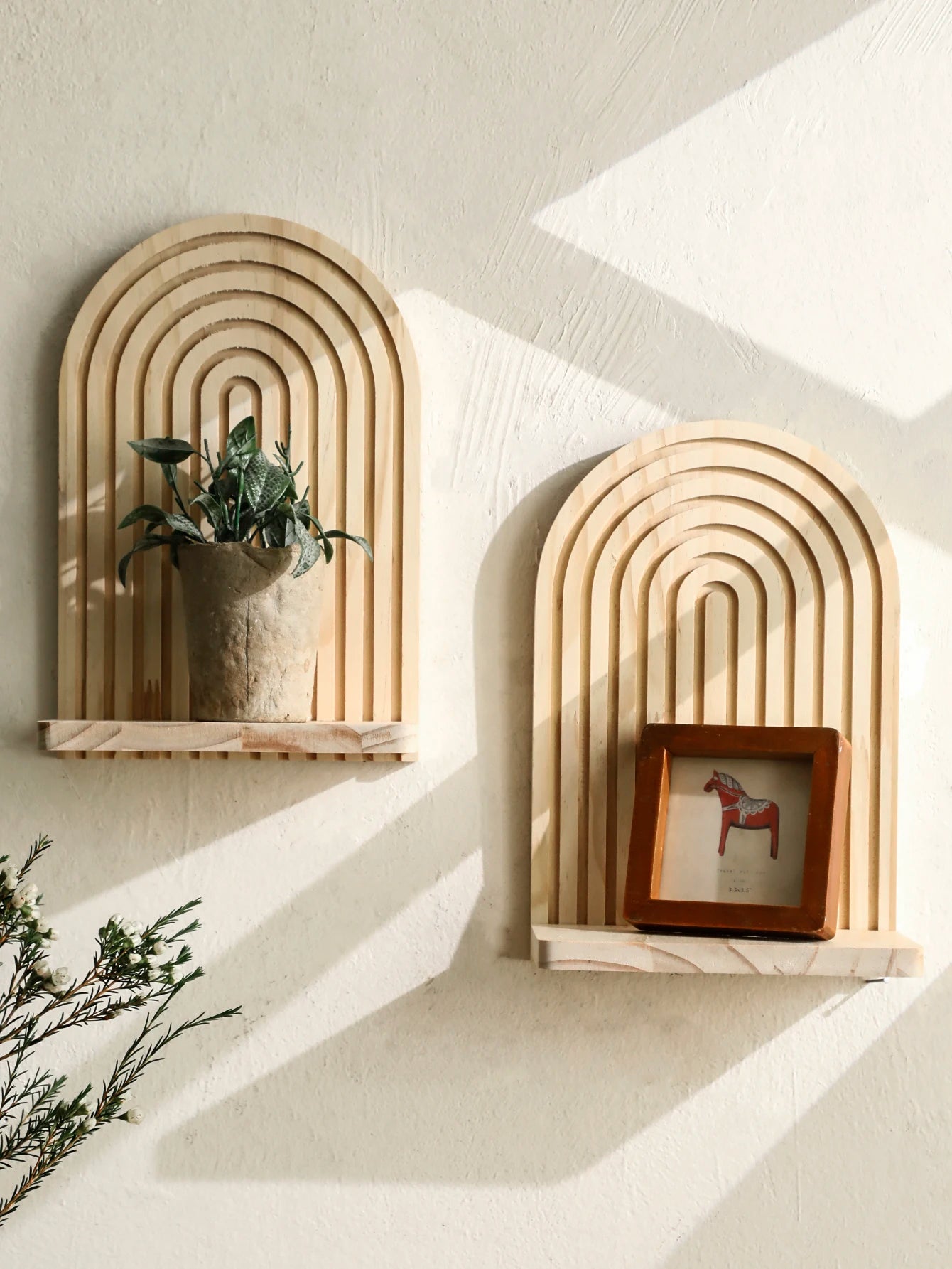 Two decorative wall shelves with arch designs on a light-colored wall.