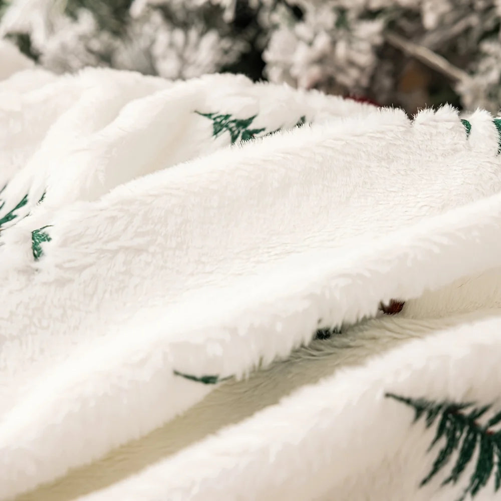 Close-up of a fluffy white blanket with green patterns, draped over a surface.