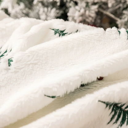 Close-up of a fluffy white blanket with green patterns, draped over a surface.