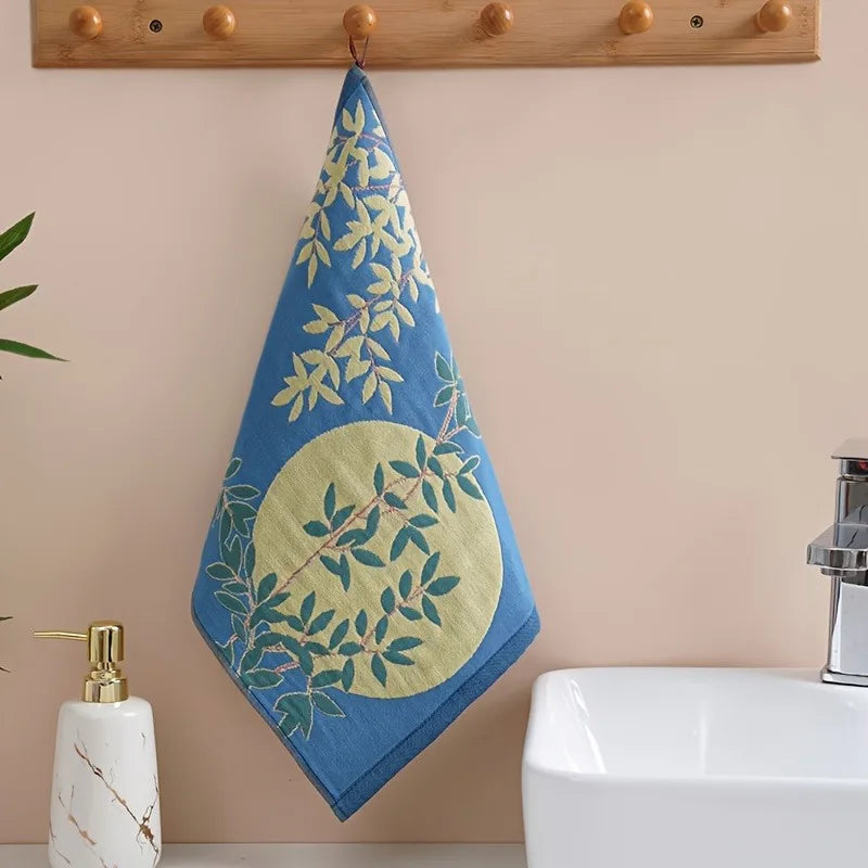 Blue tea towel with green leaf pattern hanging on a wooden towel rack above a sink.