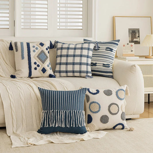 Decorative pillows on a beige sofa in a living room setting. Nordic blue tufted cushion cover with geometric stripe and grid crochet pattern, tassel pillow cover for sofa, bed, and boho home decor