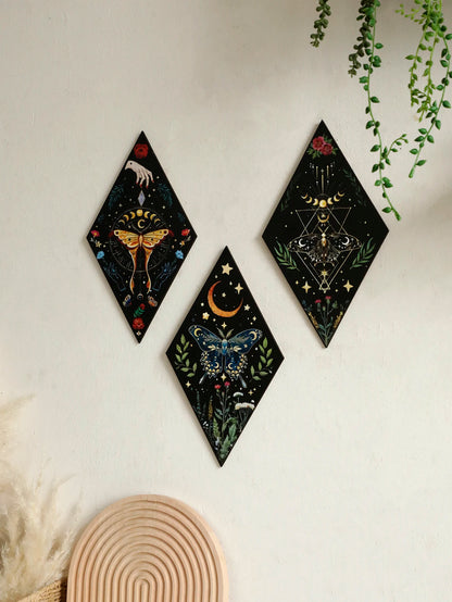 Three diamond-shaped wall art pieces with celestial designs on a white wall. Nordic-inspired wooden butterfly wall hanging displayed in entryway, perfect accent piece for boho home decoration