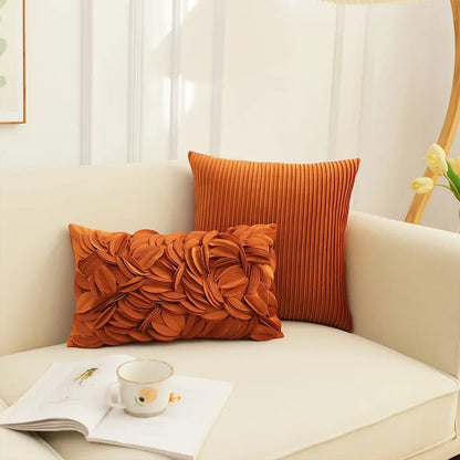 Orange textured pillows on a beige sofa with a cup and book. Boho chic embroidered cushion cover with tree and flower design