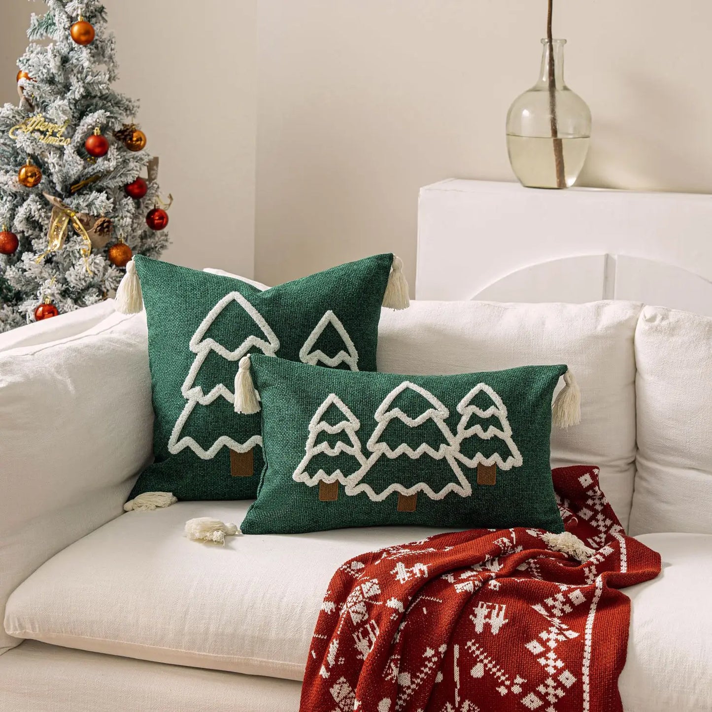 Decorative pillows with Christmas tree patterns on a white couch next to a decorated Christmas tree. tufted Christmas pillow cover with tassels, decorative festive cushion case for sofa or bed in 12x20 or 18x18 inches.