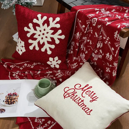 Red pillow with white snowflake design and 'Merry Christmas' pillow on a wooden surface. Embroidered Merry Christmas pillow cover with snowflake design – festive red and white holiday cushion for sofa or bedroom décor.