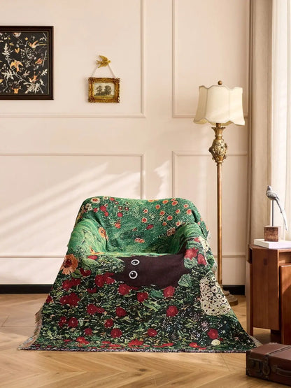 Floral-patterned blanket draped over a chair in a room with a lamp and framed pictures on the wall. Cat woven throw blanket for boho sofa and home decor