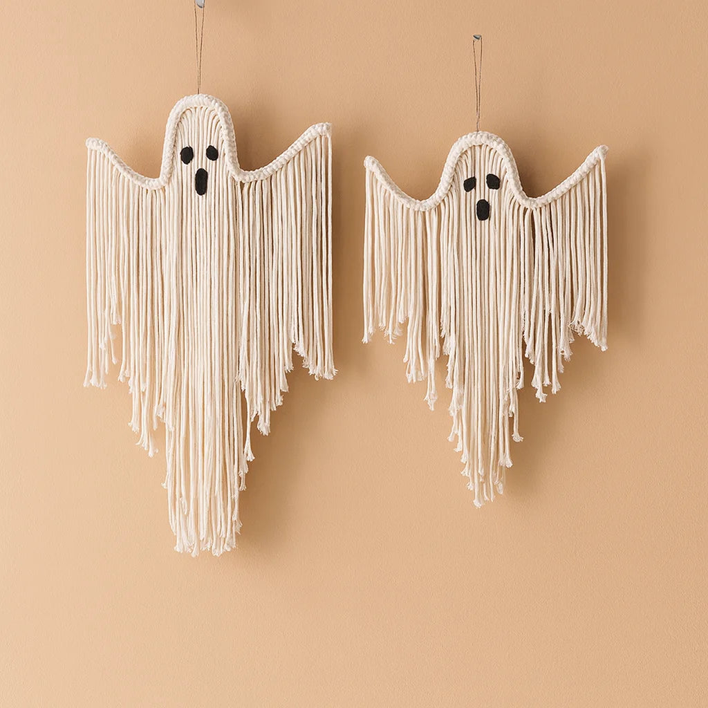 Two macrame ghost wall hangings in off-white cotton cord with black embroidered eyes and mouths, hanging against a warm beige background from My Boho Home