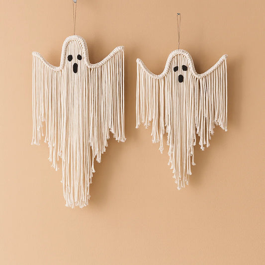 Two macrame ghost wall hangings in off-white cotton cord with black embroidered eyes and mouths, hanging against a warm beige background from My Boho Home