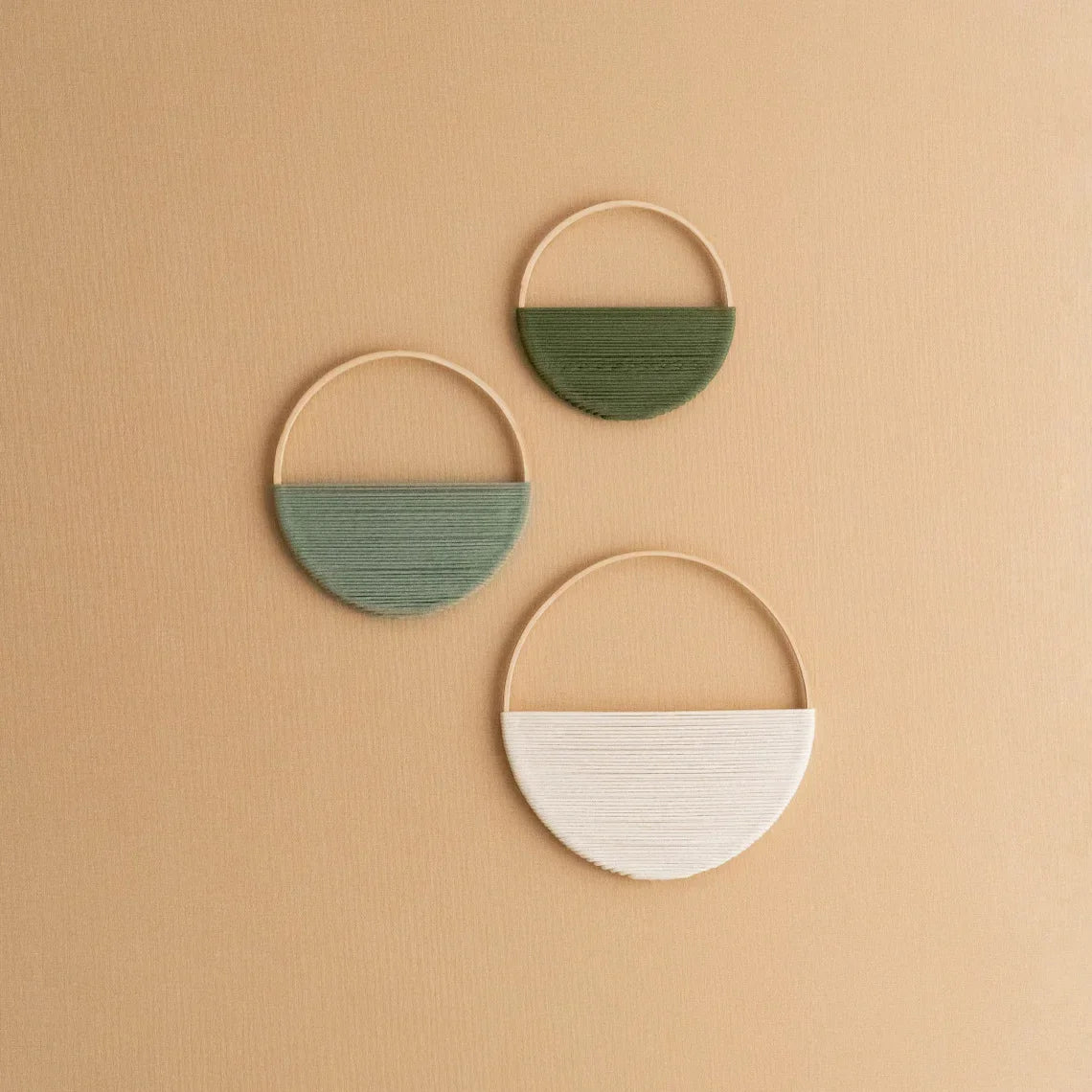 Three circular wall hangings with green and white sections on a beige background