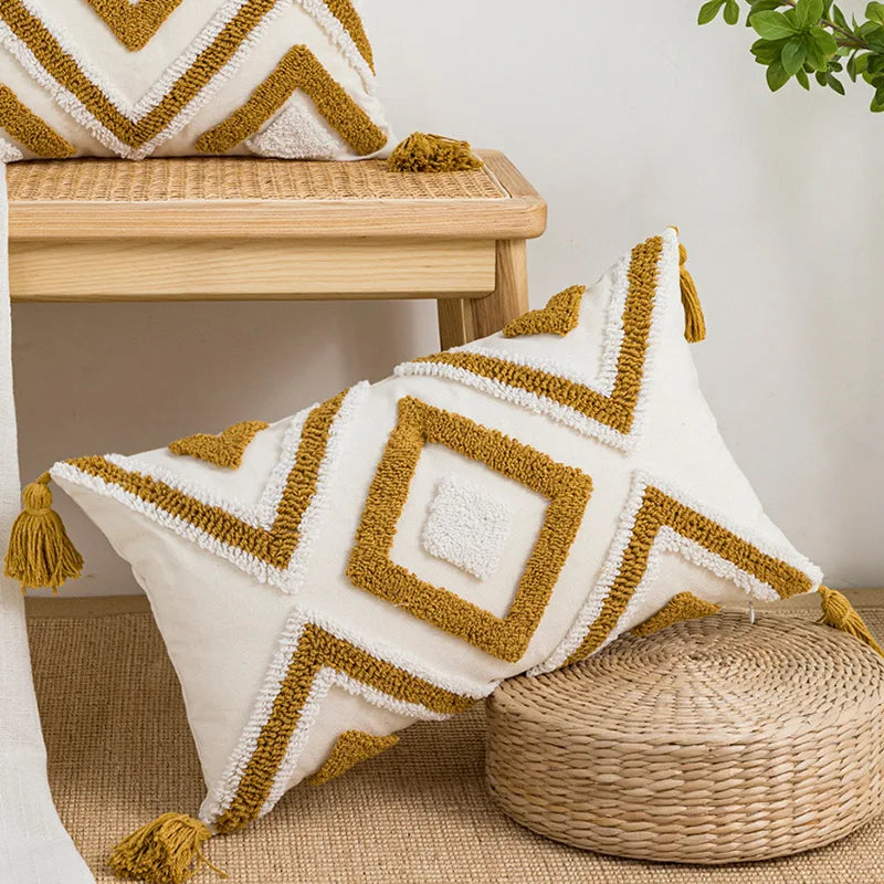 Decorative pillow with geometric pattern and tassels on a wooden stool. Nordic blue tufted cushion cover with geometric stripe and grid crochet pattern, tassel pillow cover for sofa, bed, and boho home decor