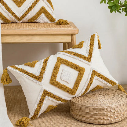 Decorative pillow with geometric pattern and tassels on a wooden stool. Nordic blue tufted cushion cover with geometric stripe and grid crochet pattern, tassel pillow cover for sofa, bed, and boho home decor
