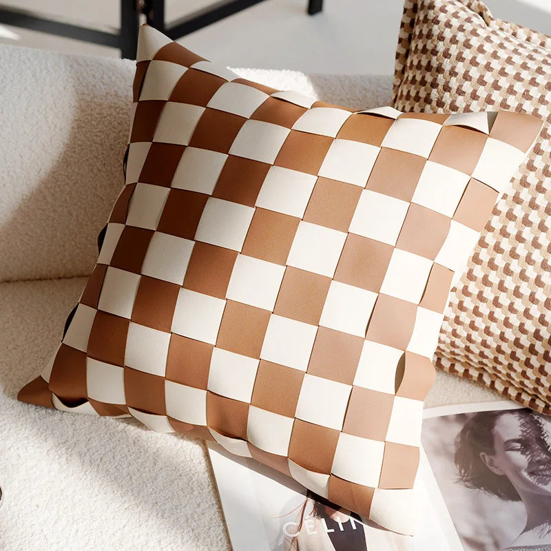 Checkered brown and beige pillow on a sofa with a blurred photo in the background