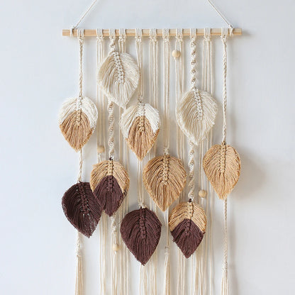 Macrame wall hanging with leaf-shaped decorations on a white background