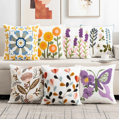 Colorful floral and butterfly patterned pillows on a sofa. Embroidered flower pillow cover, 17.7-inch square canvas cushion case with floral design for sofa, bed, and boho home decor