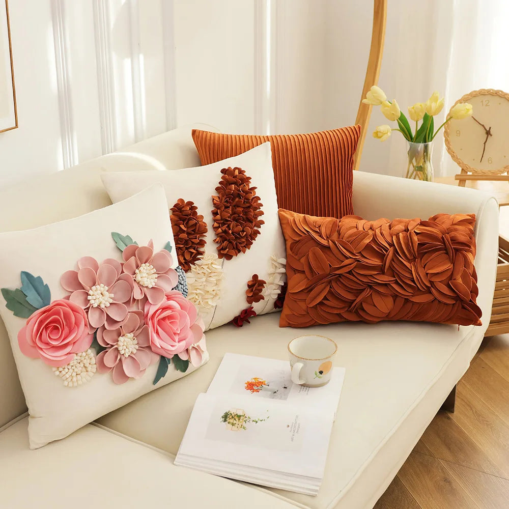 Decorative pillows on a sofa with a cup and notebook. Boho chic embroidered cushion cover with tree and flower design