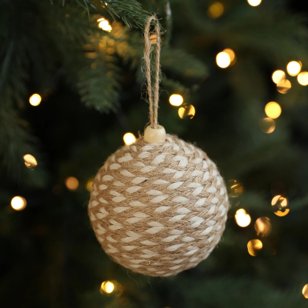 Textured ball ornament hanging on a Christmas tree with blurred lights in the background