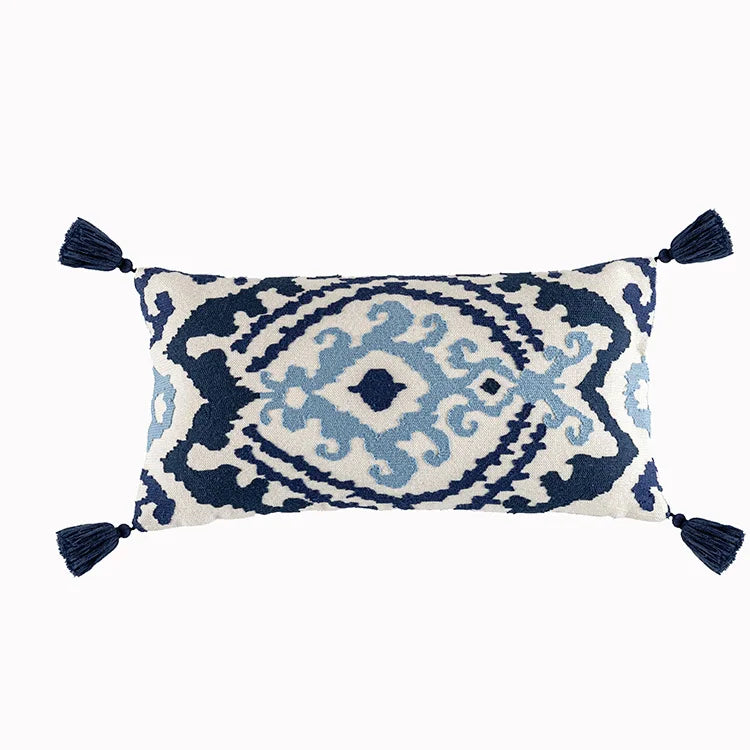 Decorative pillow with blue and white pattern and tassels on a white background. Bohemian embroidered throw pillow cover with geometric design, cotton-blend cushion for sofa, bed, or modern home decor.