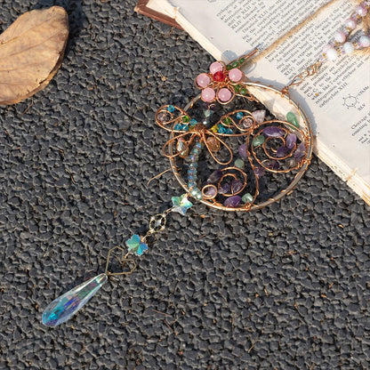 Decorative brooch with beads and a teardrop-shaped pendant on a textured surface. boho home decor, crystal wind chime, sun catcher for windows, moon prism chime, agate stone hanging, garden art decor, patio hanging decoration, boho housewarming gift, spiritual gift, crystal suncatcher, balcony decor, meditation decor, handmade crystal chime