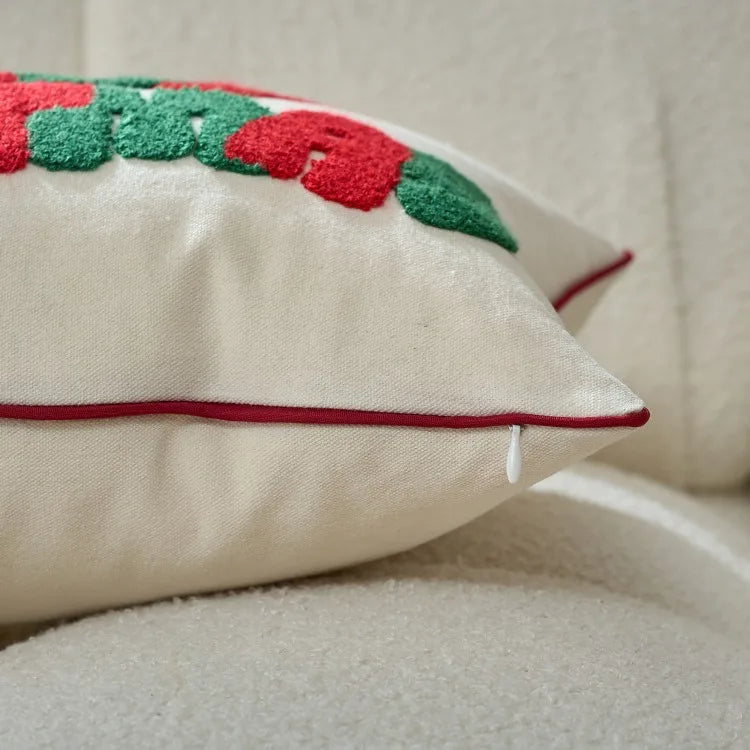 Decorative pillow with red and green floral pattern on a beige sofa.