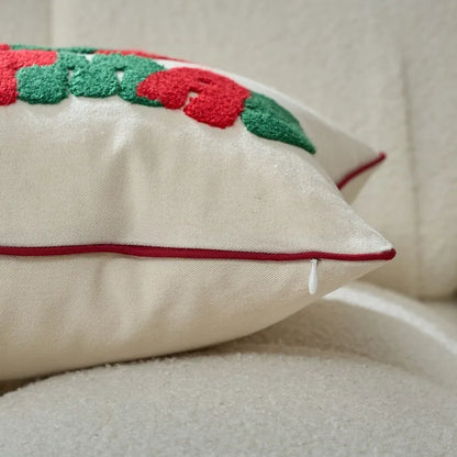Decorative pillow with red and green floral pattern on a beige sofa.