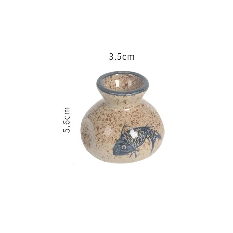 Small ceramic vase with fish design and measurements on a white background