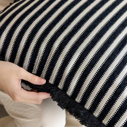 Black and white striped pillow with a hand touching it. Modern minimalist embroidered pillow cover for living room decor