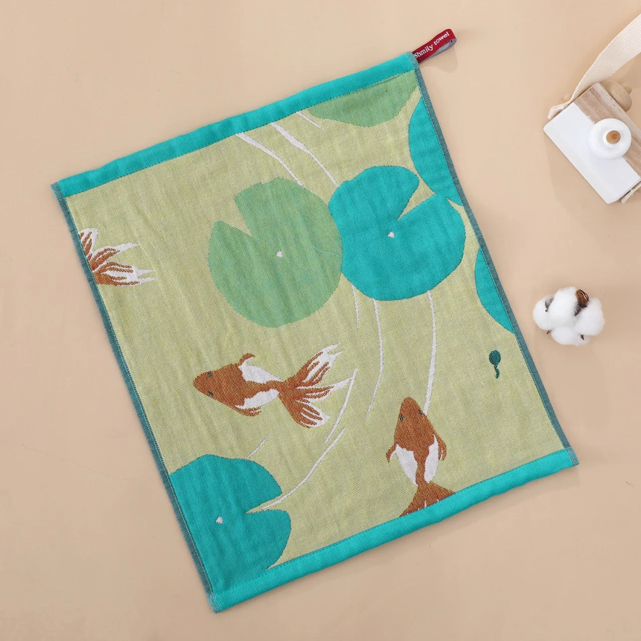 Tea towel with goldfish and lily pad design on a beige background