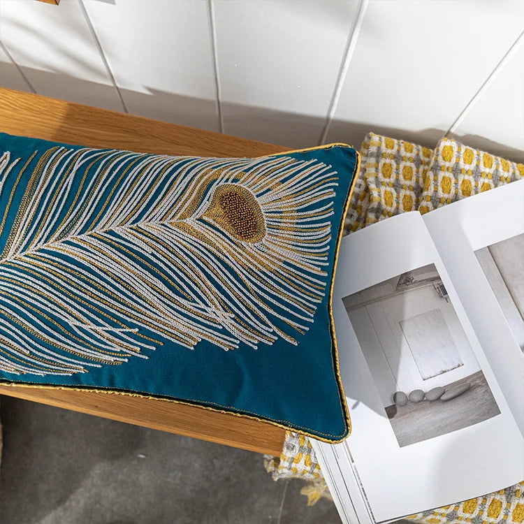 Decorative pillow with peacock feather design on a wooden surface. Bohemian embroidered throw pillow cover with geometric design, cotton-blend cushion for sofa, bed, or modern home decor.