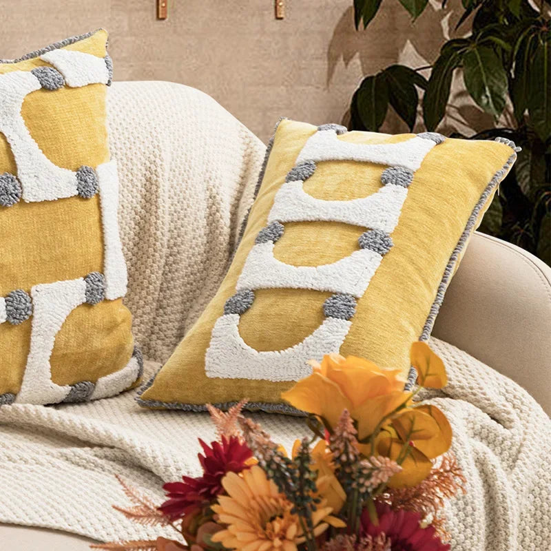 Decorative pillows with geometric patterns on a couch with a floral arrangement. Nordic blue tufted cushion cover with geometric stripe and grid crochet pattern, tassel pillow cover for sofa, bed, and boho home decor