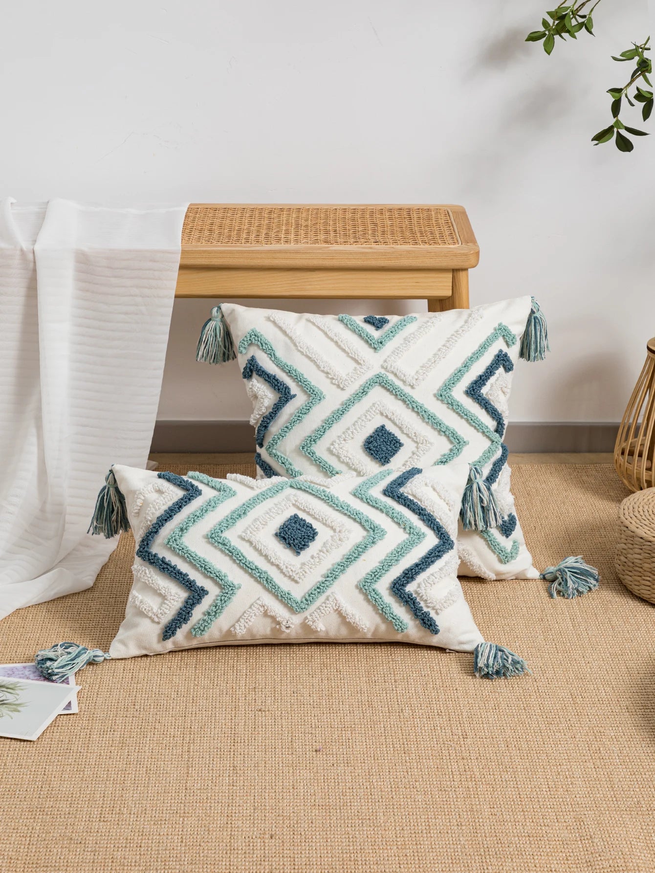 Decorative pillows with geometric patterns and tassels on a beige surface.