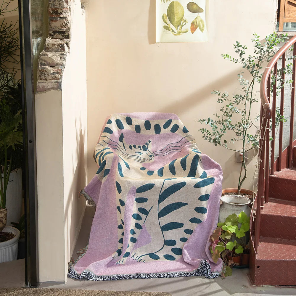 Floral-patterned blanket draped over a chair in a home setting with plants and a staircase. Pink cat cartoon throw blanket boho cotton sofa cover
