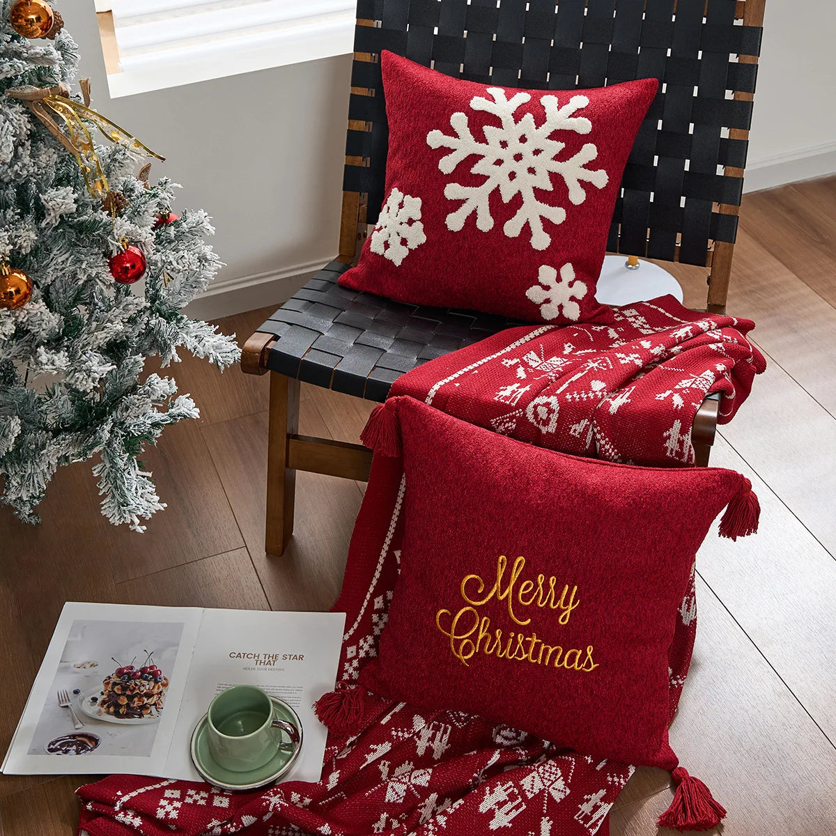 Decorative Christmas scene with red pillows and blanket on a chair next to a Christmas tree. Embroidered Merry Christmas pillow cover with snowflake design – festive red and white holiday cushion for sofa or bedroom décor.