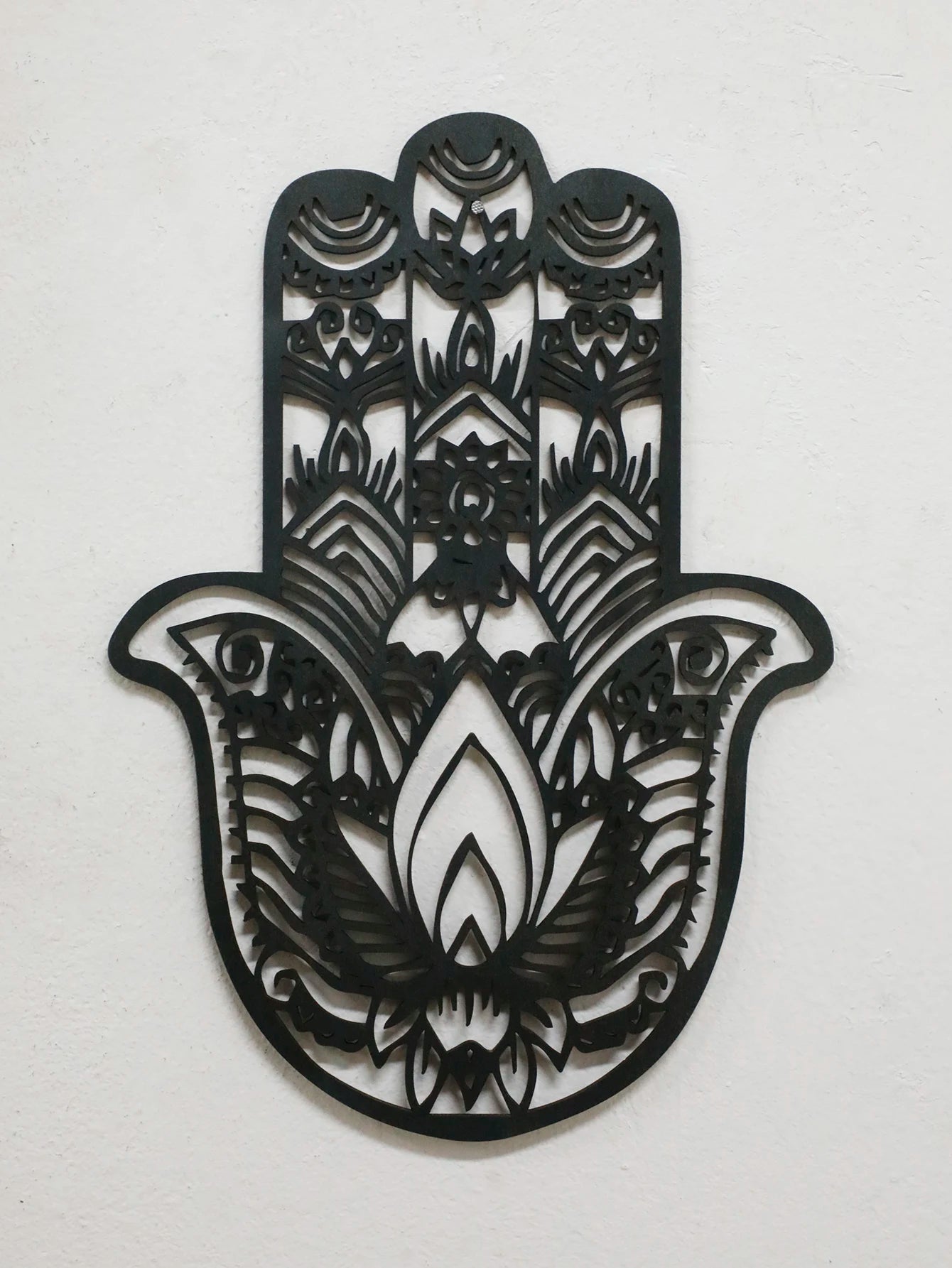 Black hand-shaped wood wall decor with protective evil eye, photographed against neutral background for alternative room styling.
