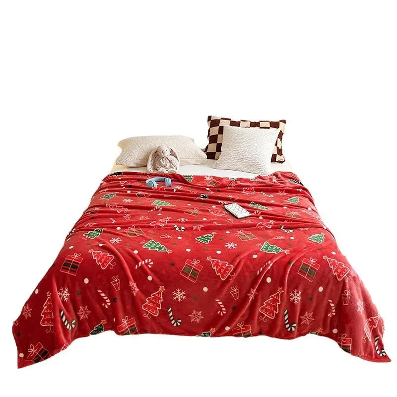 Red Christmas-themed blanket on a bed with white pillows.