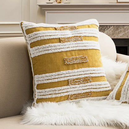 Textured yellow and white pillow on a beige sofa with a fireplace in the background Nordic blue tufted cushion cover with geometric stripe and grid crochet pattern, tassel pillow cover for sofa, bed, and boho home decor