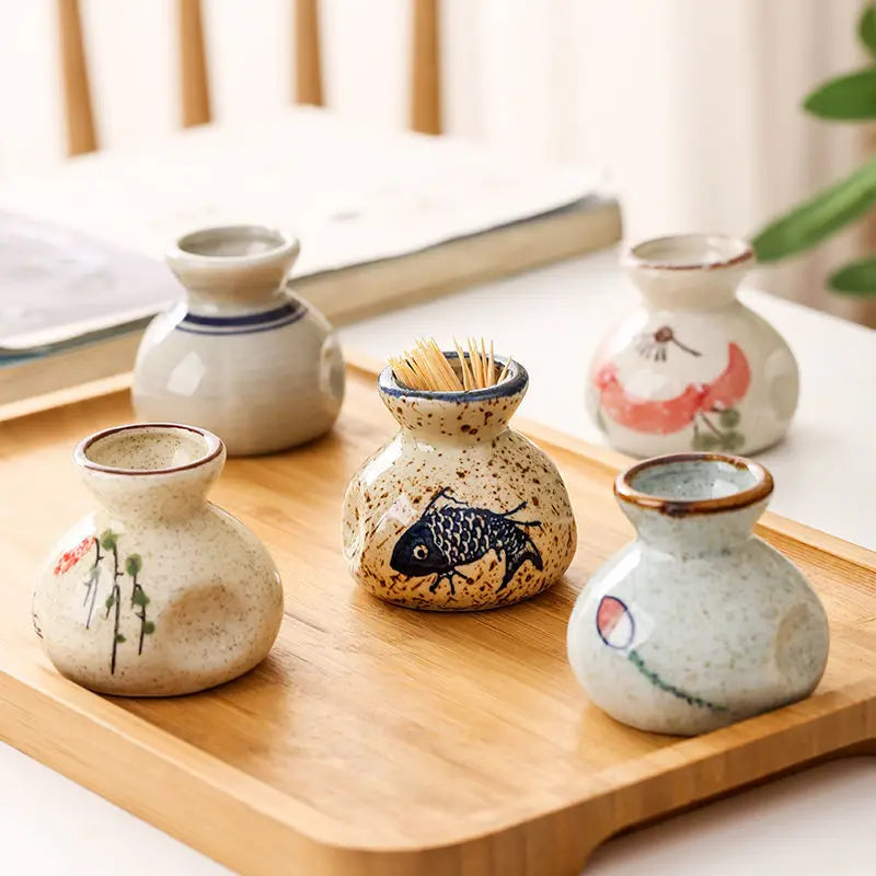 Set of small ceramic containers with artistic designs on a wooden tray.