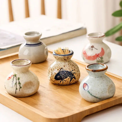 Set of small ceramic containers with artistic designs on a wooden tray.