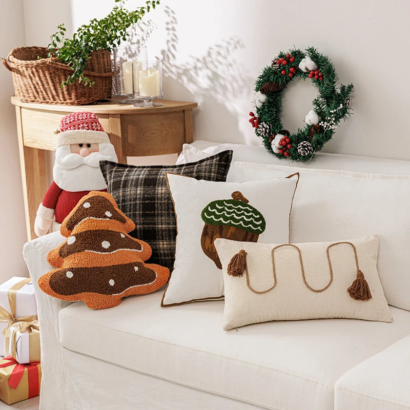 Decorative pillows on a couch with a Christmas wreath and gifts in the background
