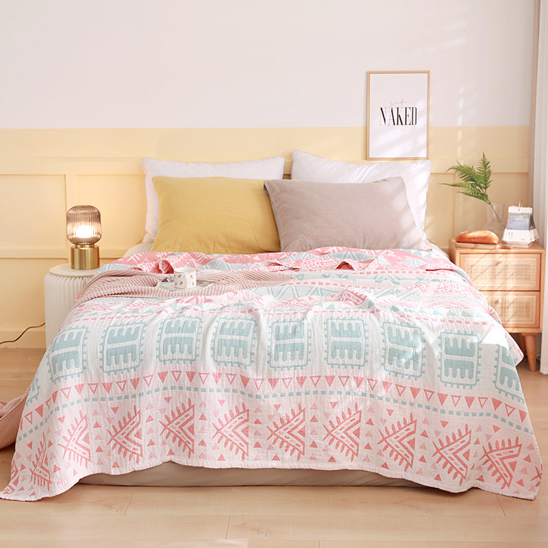 Bed with a patterned quilt, pillows, and nightstands in a bedroom setting. Boho Lightweight microfiber summer blanket for bed or sofa, cooling breathable throw for home, dorm, or office naps with geometric jacquard pattern.