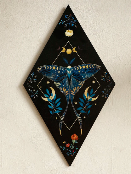 Decorative wall art with a blue moth design on a black diamond-shaped canvas. Rustic colorful wood wall art panel with moon, stars, and butterfly engraving, displayed above a sofa in a boho-styled living room