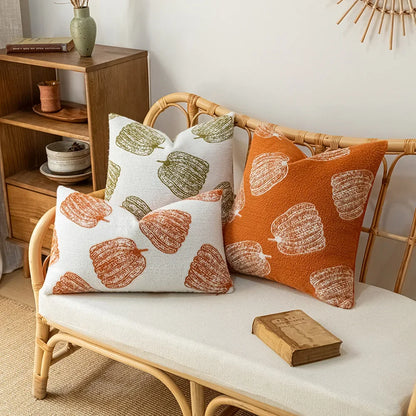 Decorative pillows with autumnal patterns on a wicker bench in a cozy room. Cozy fall pumpkin pillow cover for living room or bedroom
