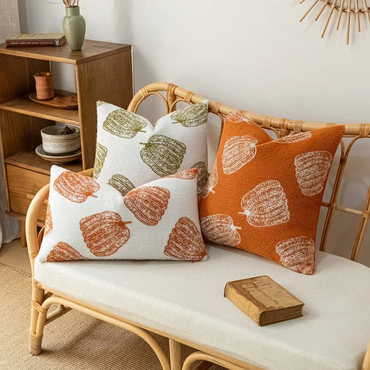 Decorative pillows with autumnal patterns on a wicker bench in a cozy room. Cozy fall pumpkin pillow cover for living room or bedroom