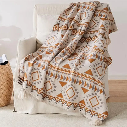Patterned Bohemian blanket draped over a chair in a room with a neutral color scheme.